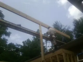 Carpenter setting a ridge beam over a new addition frame — Ice Dam Removal by Roofing Brothers in Brodnax