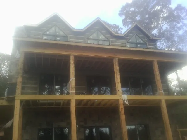 Dormers and porch framing on a large log home under construction — Roof Coating work by our crew in Brodnax