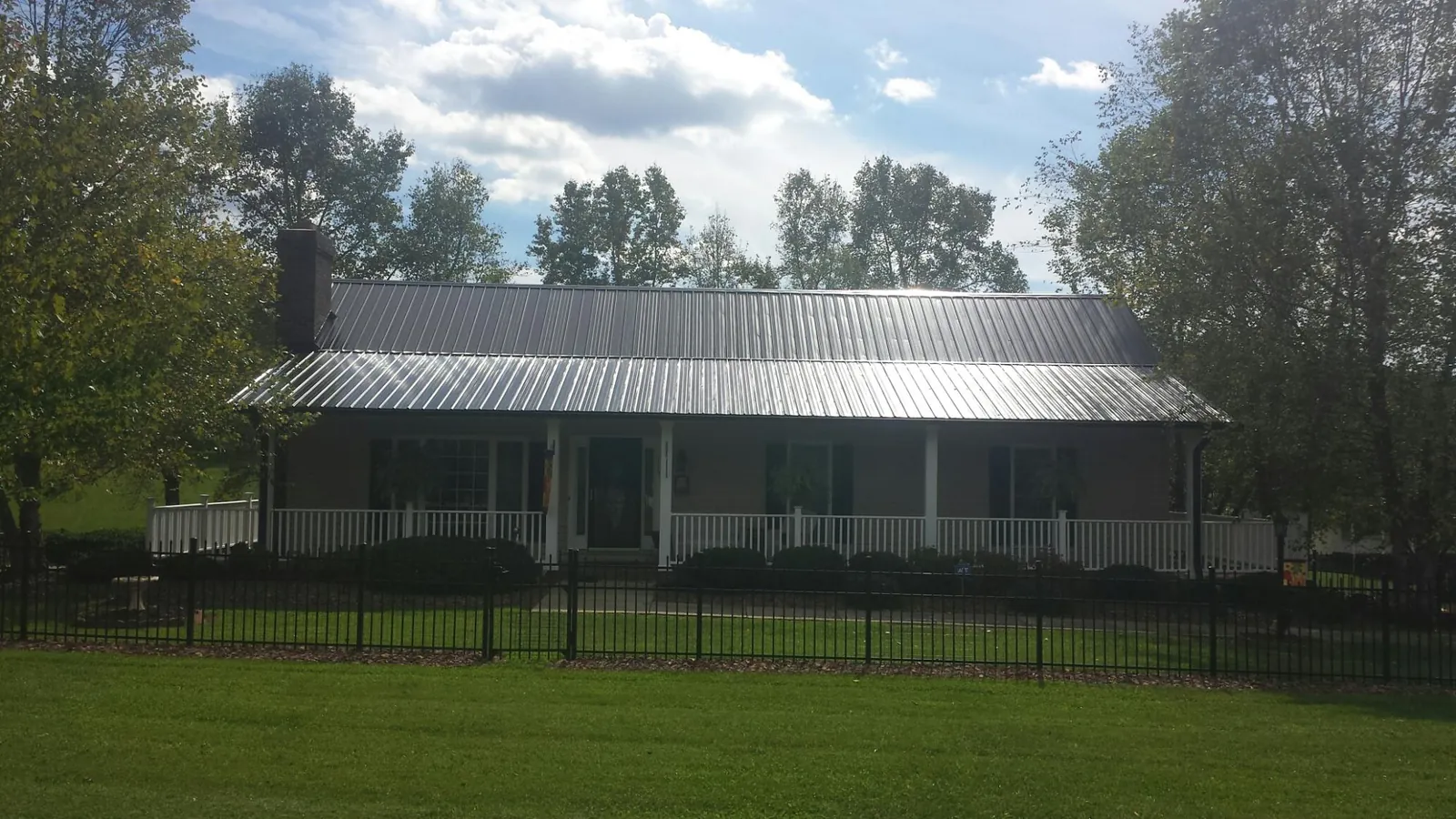 Gray metal roof on a brick ranch with a full width front porch — Gutter Guard Installation work by our crew in Brodnax